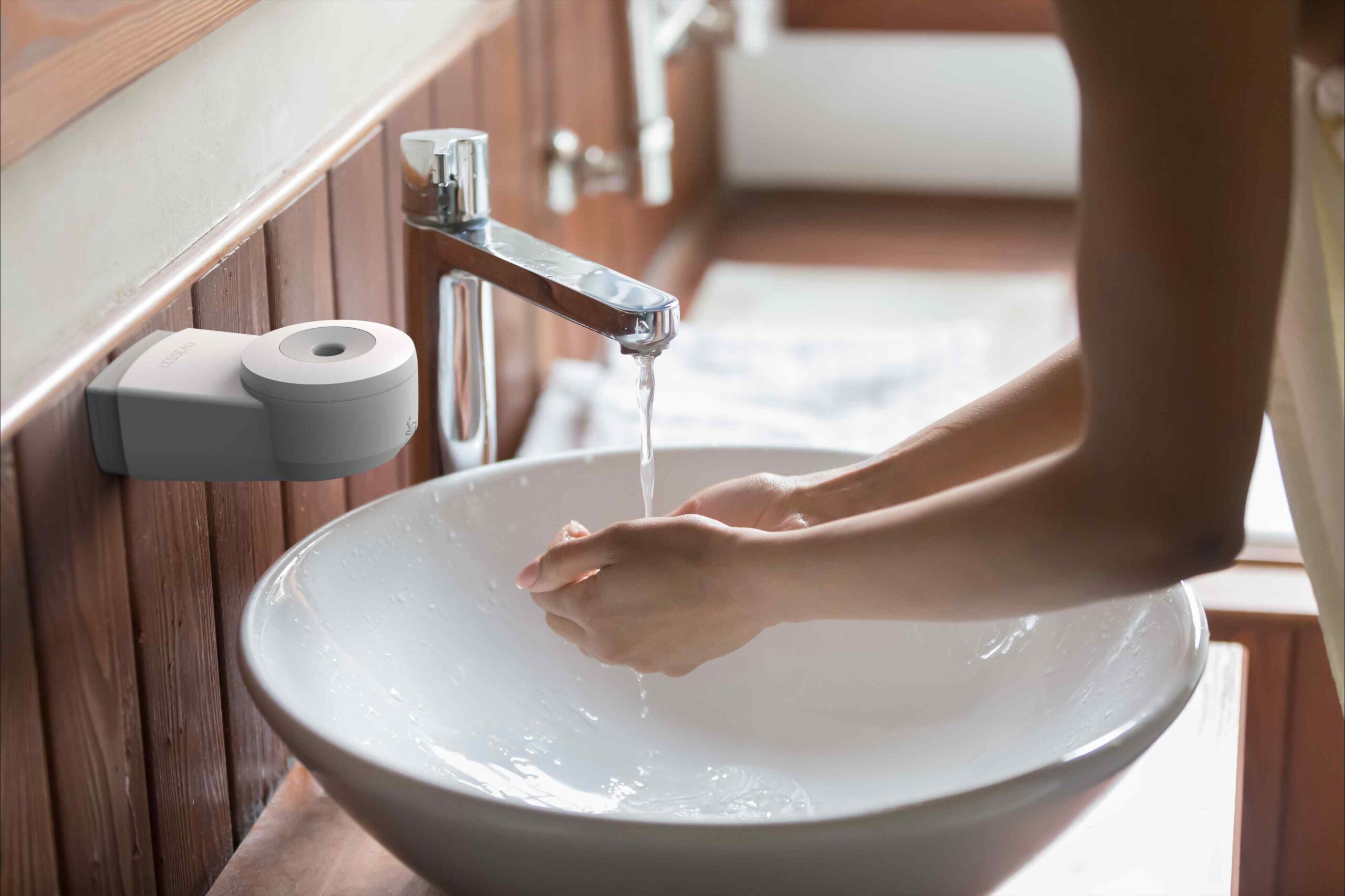 Persoon die handen wast in wasbak met no-touch zeepdispenser en handzeep in zeepdispenser van Lesseau
