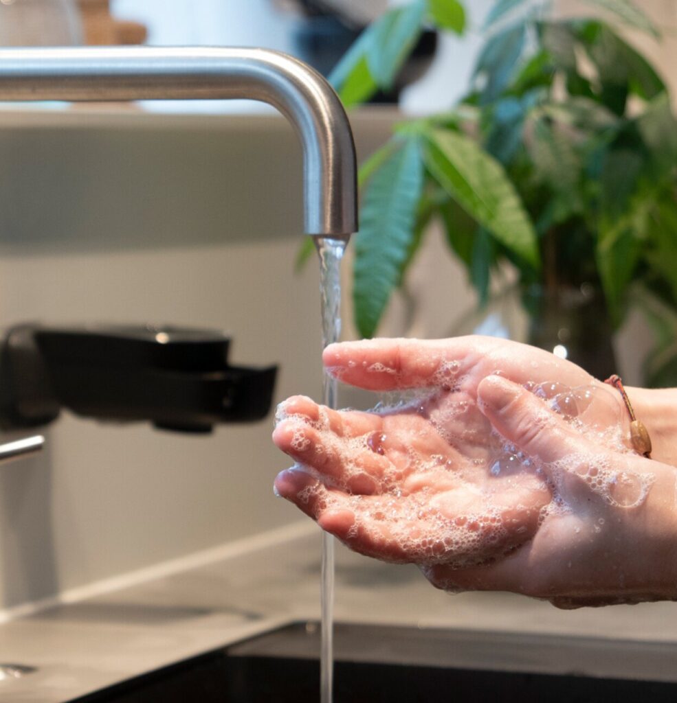 Persoon wast handen met Lesseau zeepdispenser